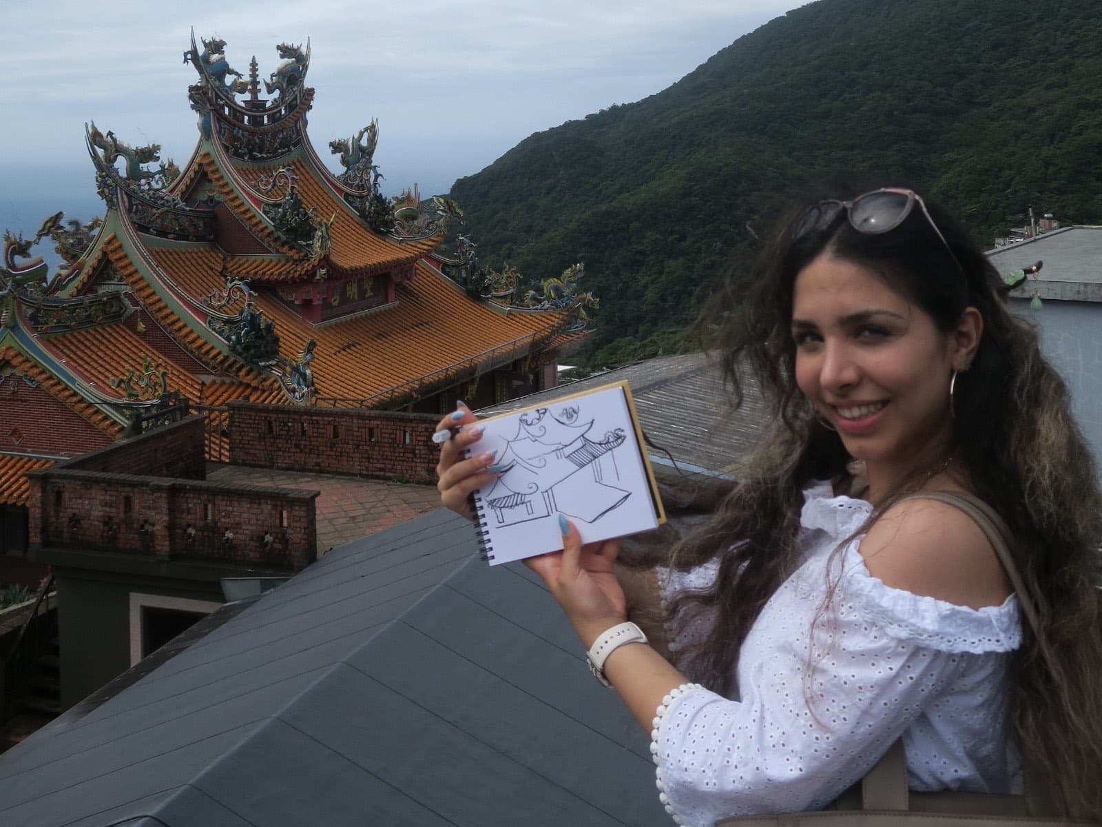 Nika Sahih sketching a temple in a notebook while travelling